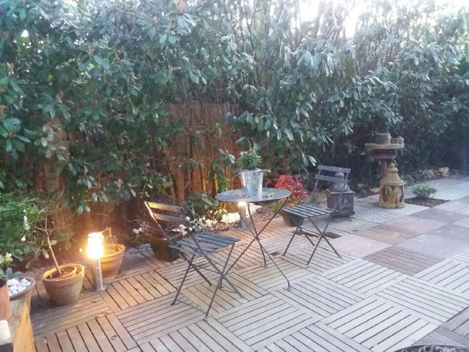 um pátio com uma mesa e cadeiras num jardim em Chez les Dom’s em Sainte-Cécile