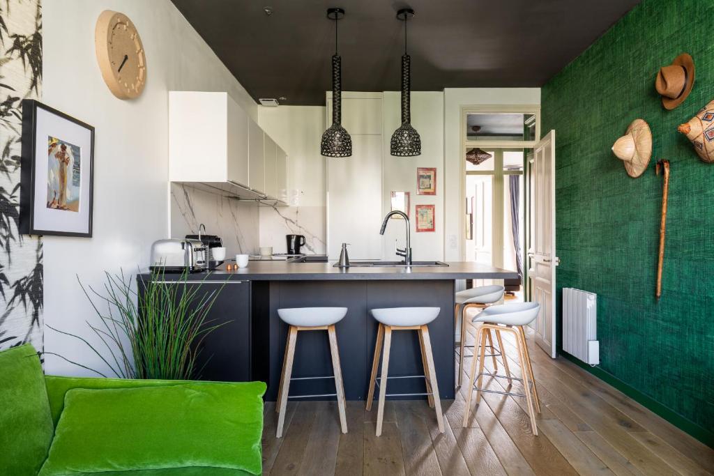 a kitchen with green walls and a counter and stools at DIFY Art Déco - Charpennes in Villeurbanne