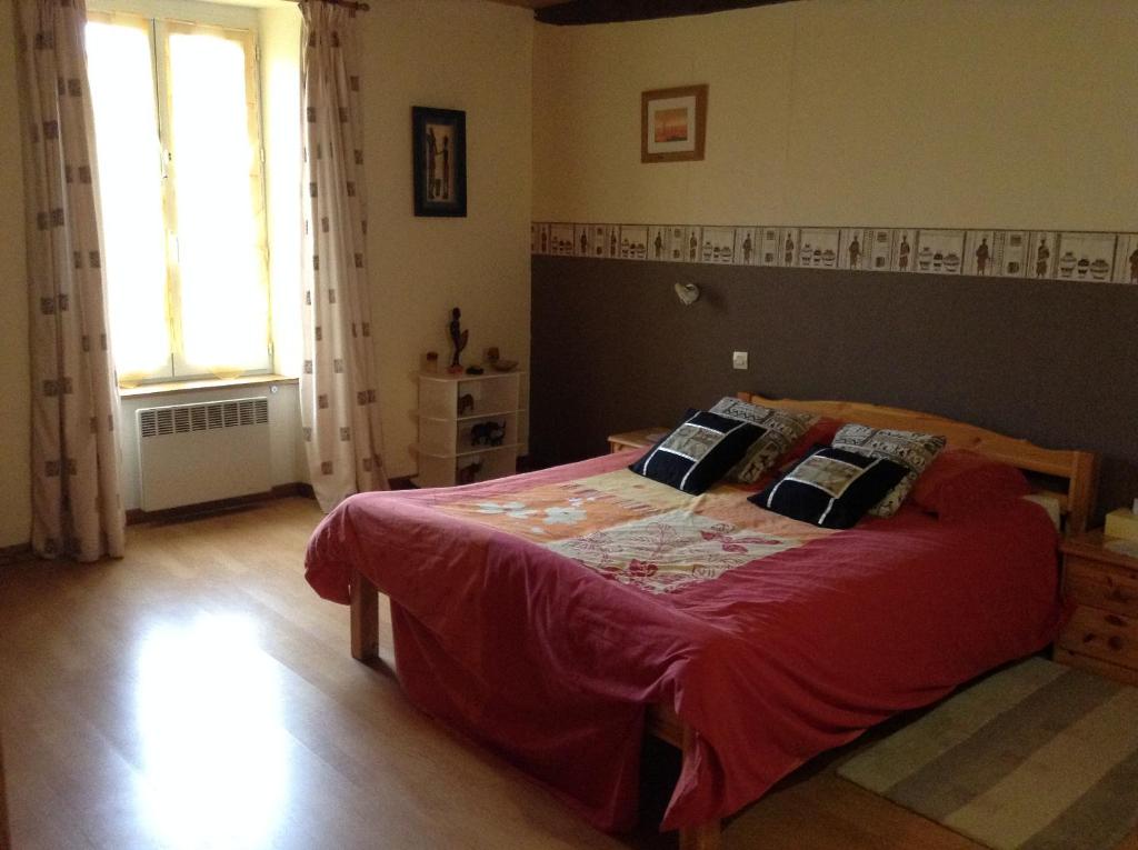 Schlafzimmer mit einem Bett mit roter Bettwäsche und einem Fenster in der Unterkunft Le Bois Chef D'Ane in Collinée