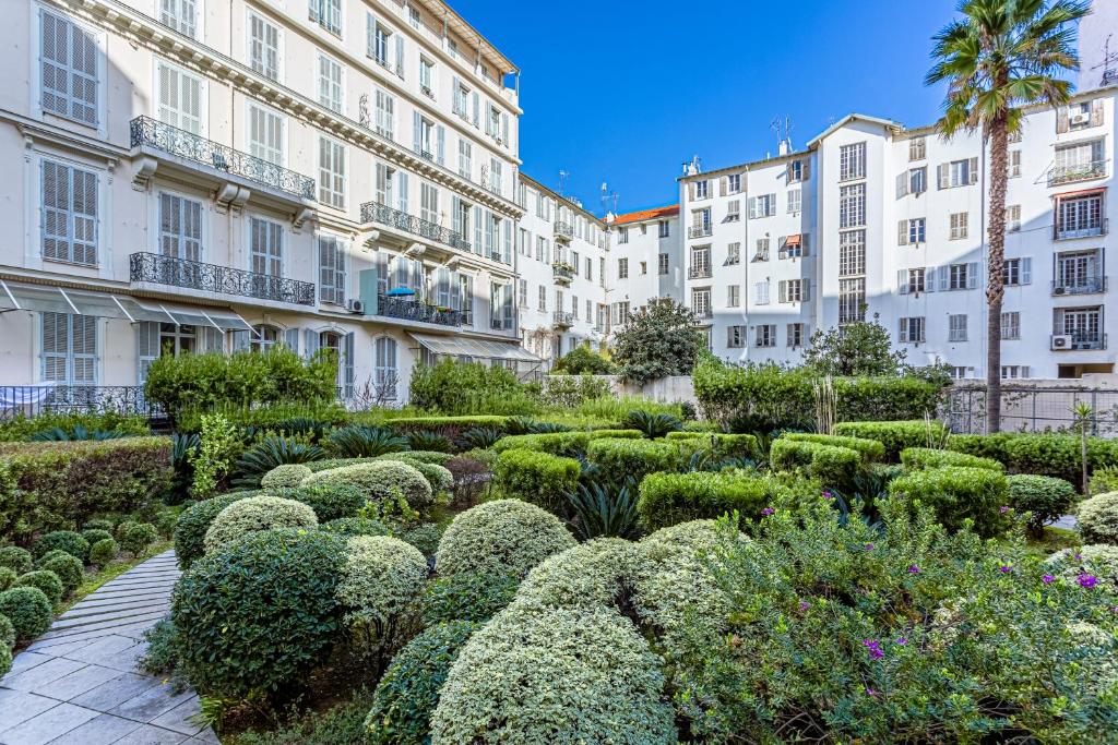 a garden in front of buildings with bushes and trees at My CASA - PALAIS DE LA MÉDITERRANÉE in Nice