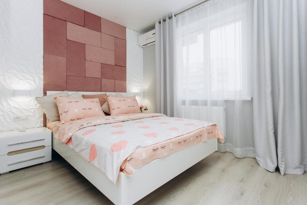 - une chambre avec un lit rose et blanc et une fenêtre dans l'établissement Apart-Hotel, à Soumy