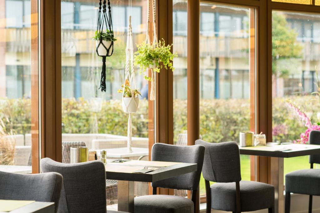 een restaurant met tafels en stoelen en een raam bij Hotel Nes in Nes
