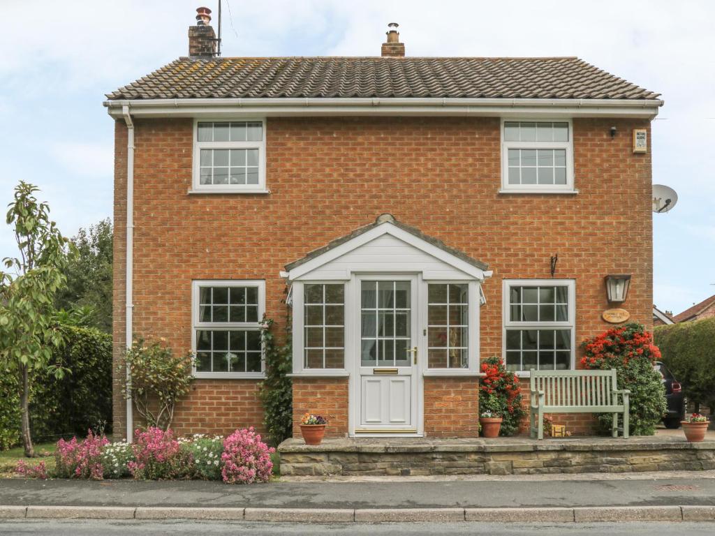 una casa di mattoni rossi con una porta bianca di Humble Bee Cottage a Great Driffield