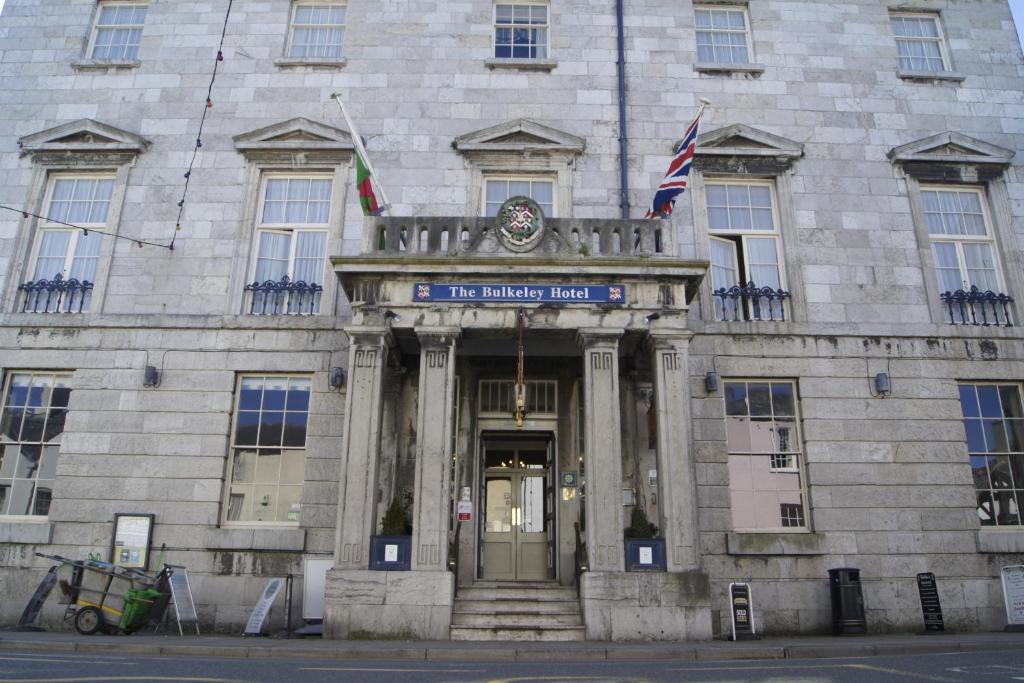 un bâtiment en pierre avec deux drapeaux devant lui dans l'établissement The Bulkeley Hotel, à Beaumaris