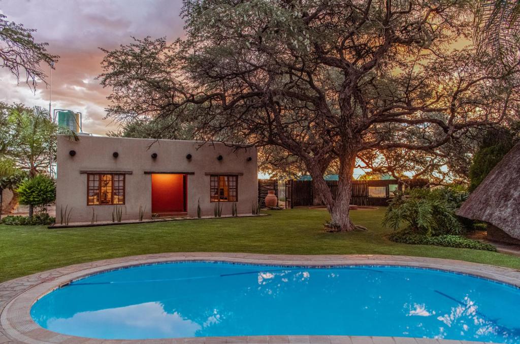 a house with a pool in front of a yard at Farmstay Okakeua in Okahandja