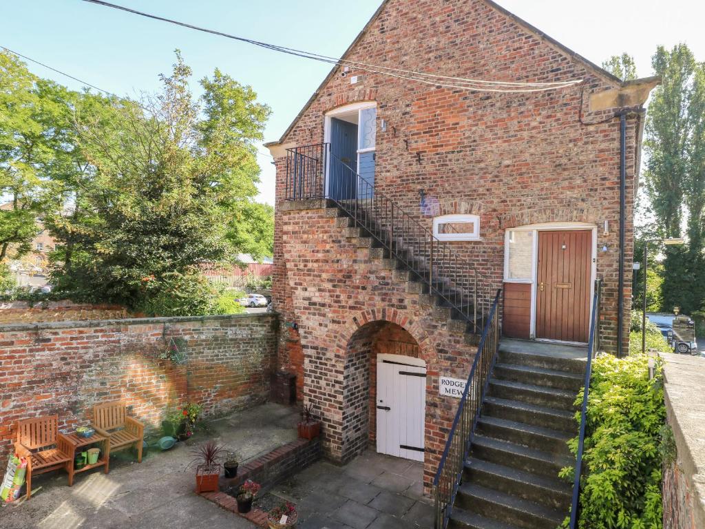 a brick house with a staircase leading up to a door at 2 Rodgers Mews in Malton