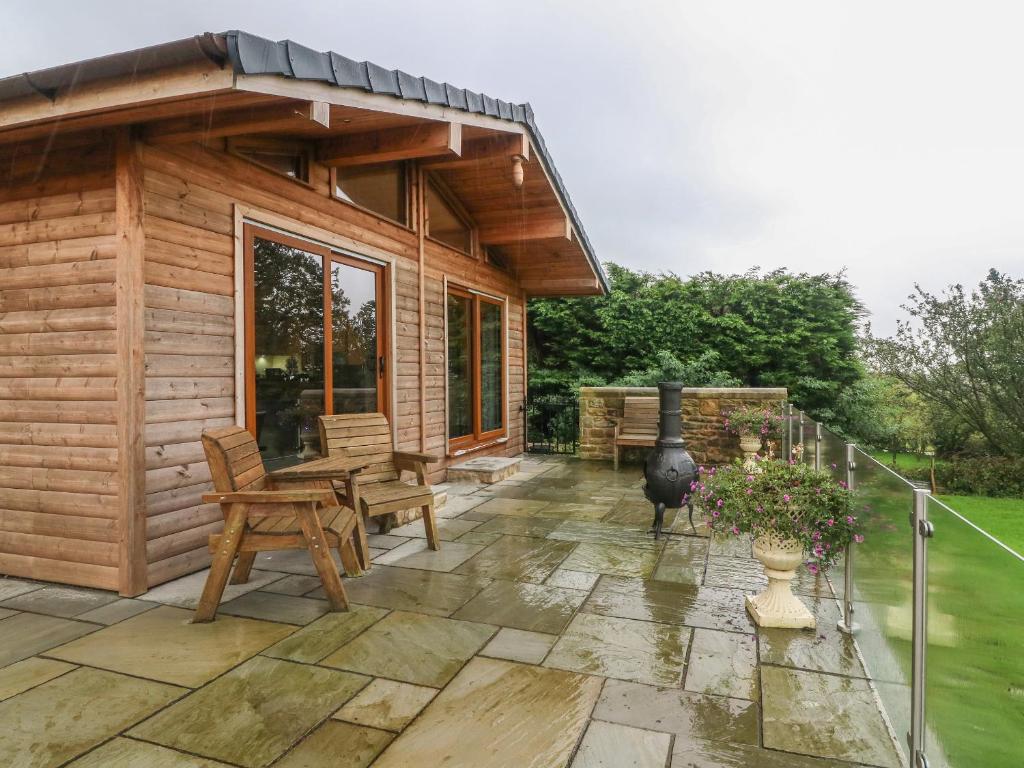 a wooden cabin with a patio with a table and chairs at Nicky Nook Lodge in Preston