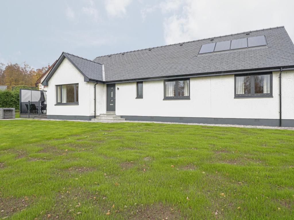 a white house with a lawn in front of it at Emsa House in Spean Bridge