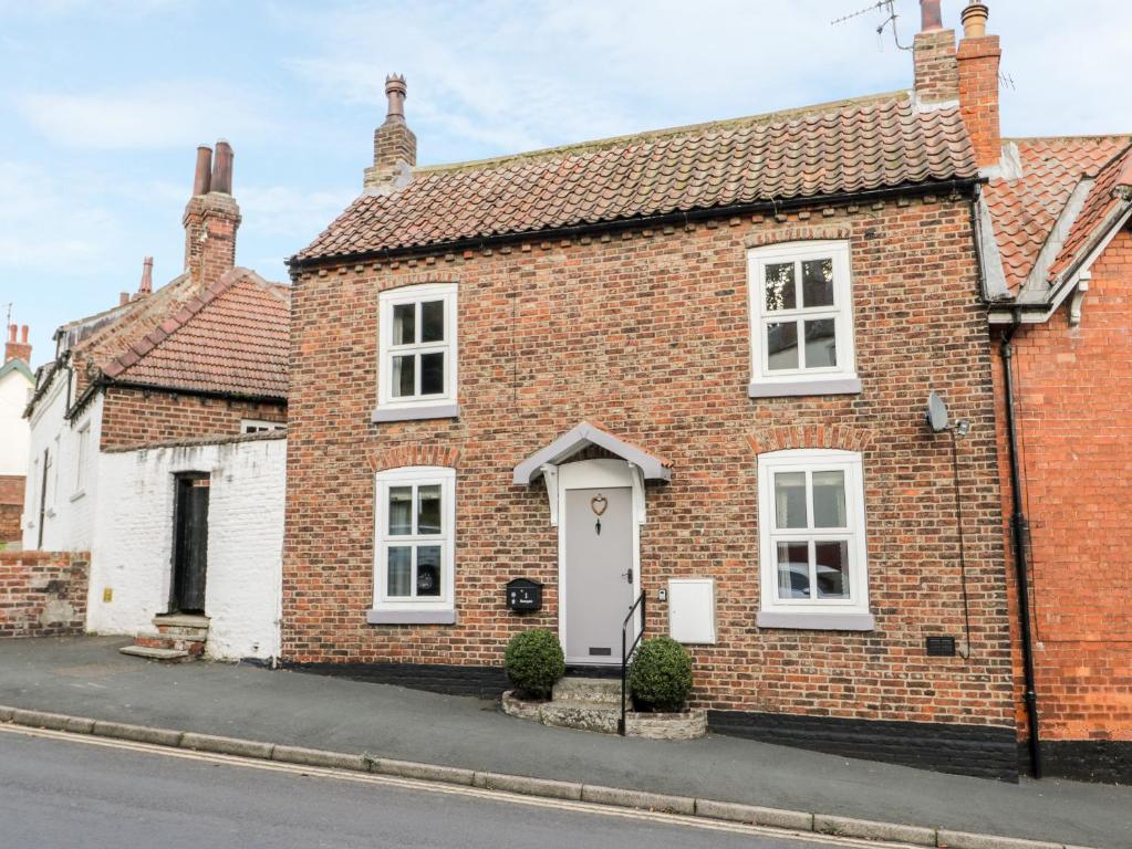 a brick house with a white door on a street at Rosie Cottage in Filey