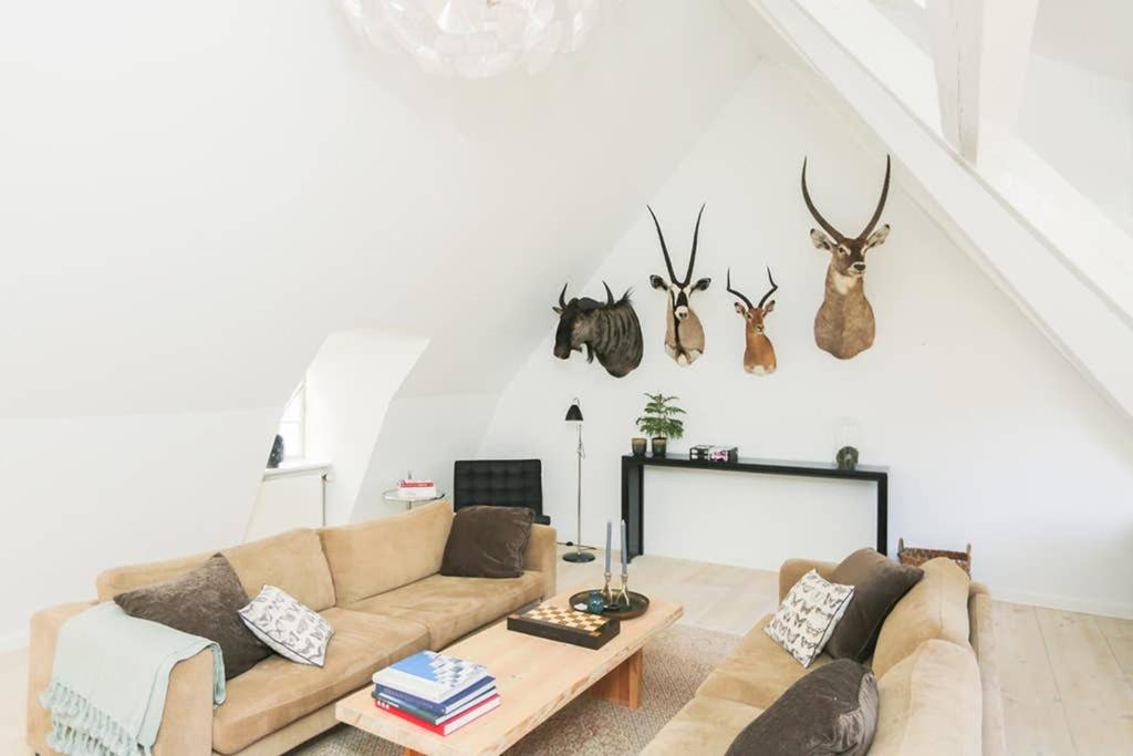 a living room with a couch and antlers on the wall at Exclusive and central - Private roof top terrace! in Copenhagen