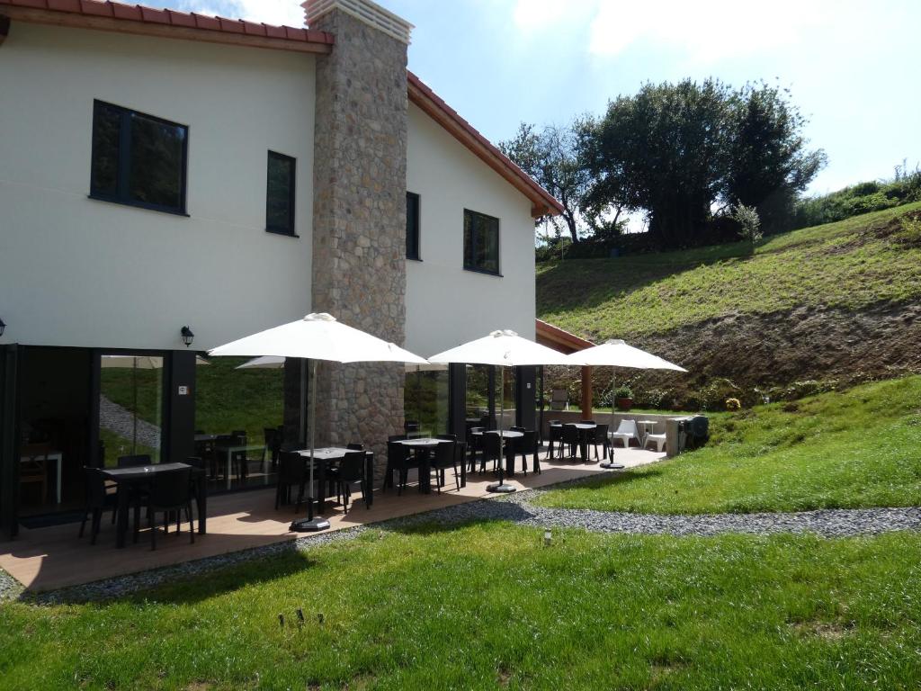 a patio with tables and umbrellas in front of a building at Hotel Casa Sueño in Salas