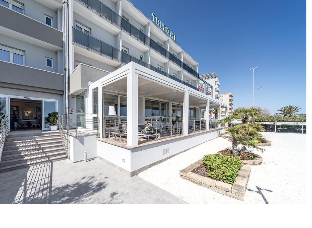 a hotel building with a restaurant in front of it at Hotel Tritone in Senigallia