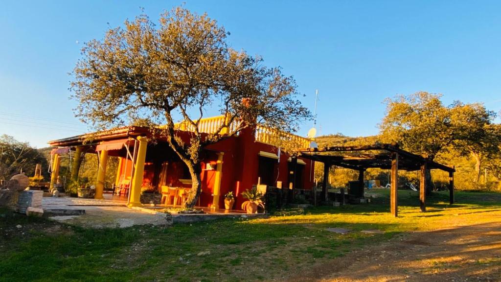 a red building with a tree in front of it at La Cañada in Villaharta