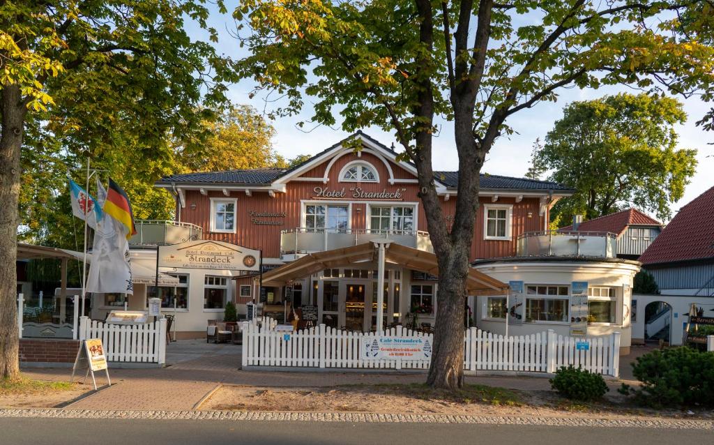 ein Gebäude mit einem weißen Zaun davor in der Unterkunft Hotel & Café Strandeck in Prerow