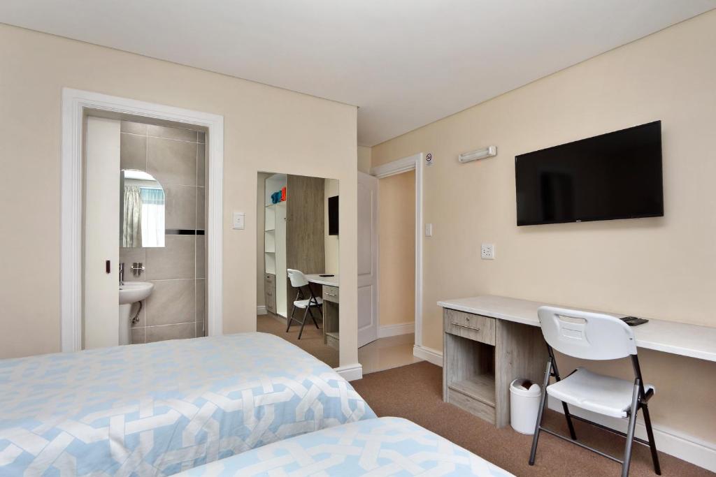 - une chambre avec un lit, un bureau et une télévision dans l'établissement Camdene Guesthouse, au Cap