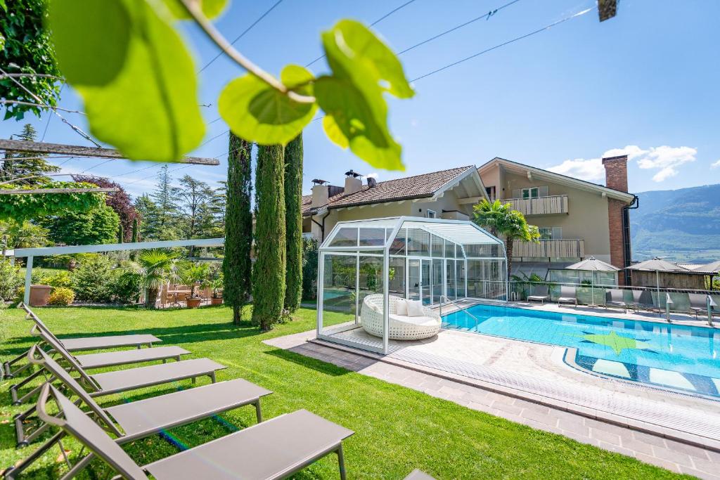 een herenhuis met een zwembad en een glazen huis bij Tirolerin Garni Hotel in Termeno