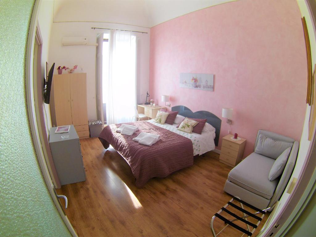 una camera con letto, sedia e specchio di Duomo Sant'Agata Apartments a Catania