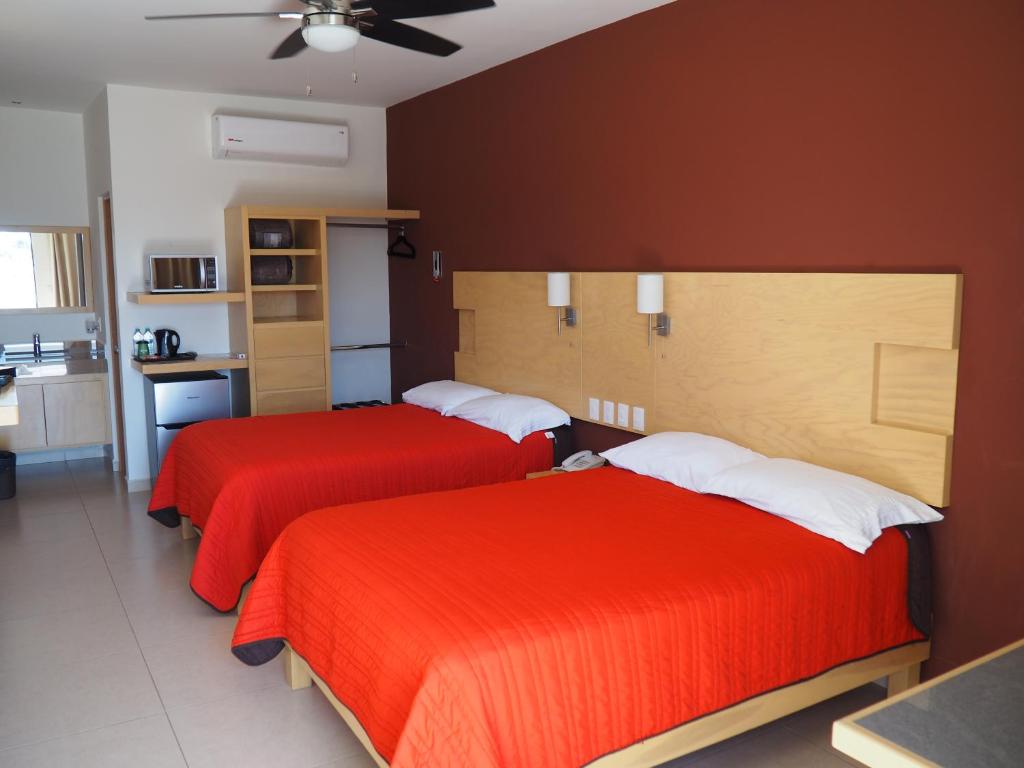 two beds in a hotel room with red sheets at Nova Hotel in Cadereyta Jim&eacute;nez