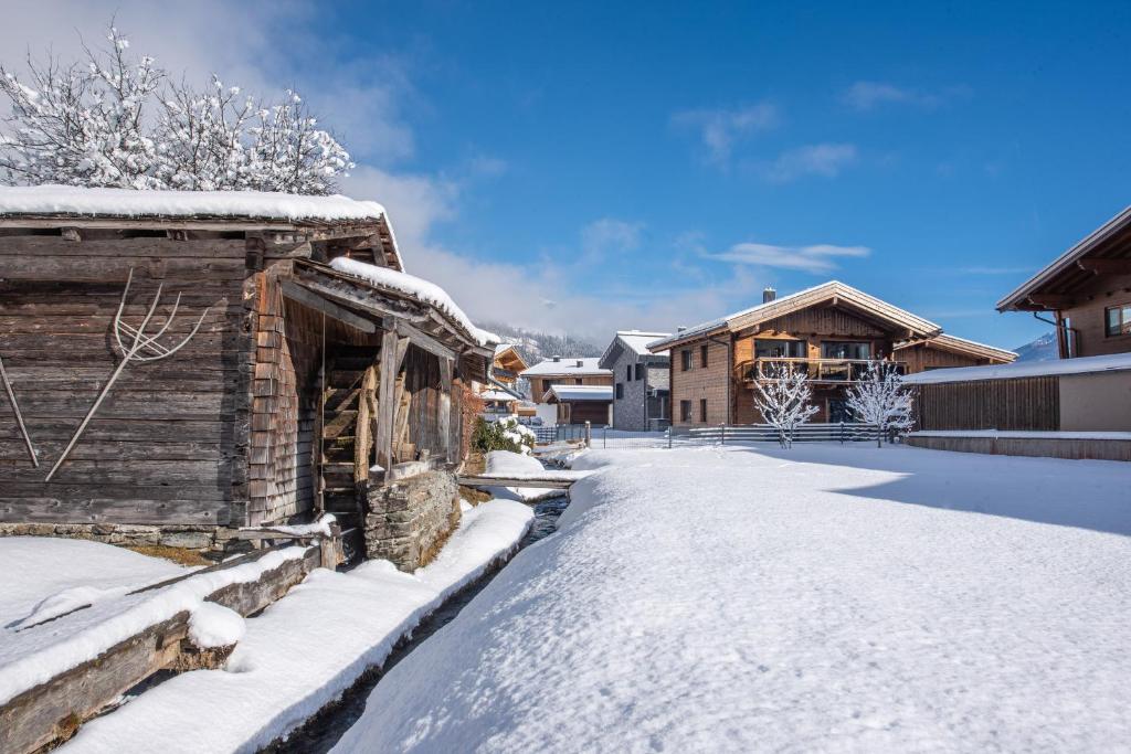 a snow covered yard with a log house at Chalet's DAS DORF in Wald im Pinzgau