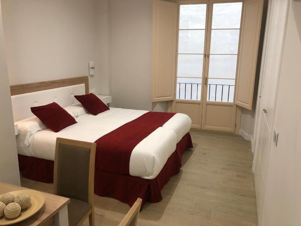 una camera da letto con un grande letto con cuscini rossi di Pinar Malaga Rooms a Málaga