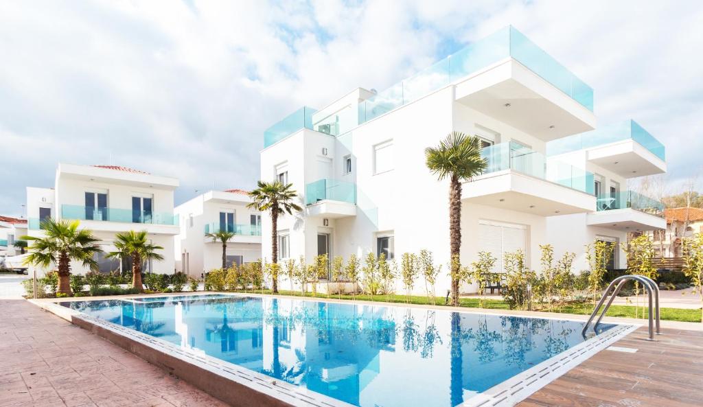 a villa with a swimming pool in front of a building at Acrotel Porto Brava Luxury Villas in Ormos Panagias