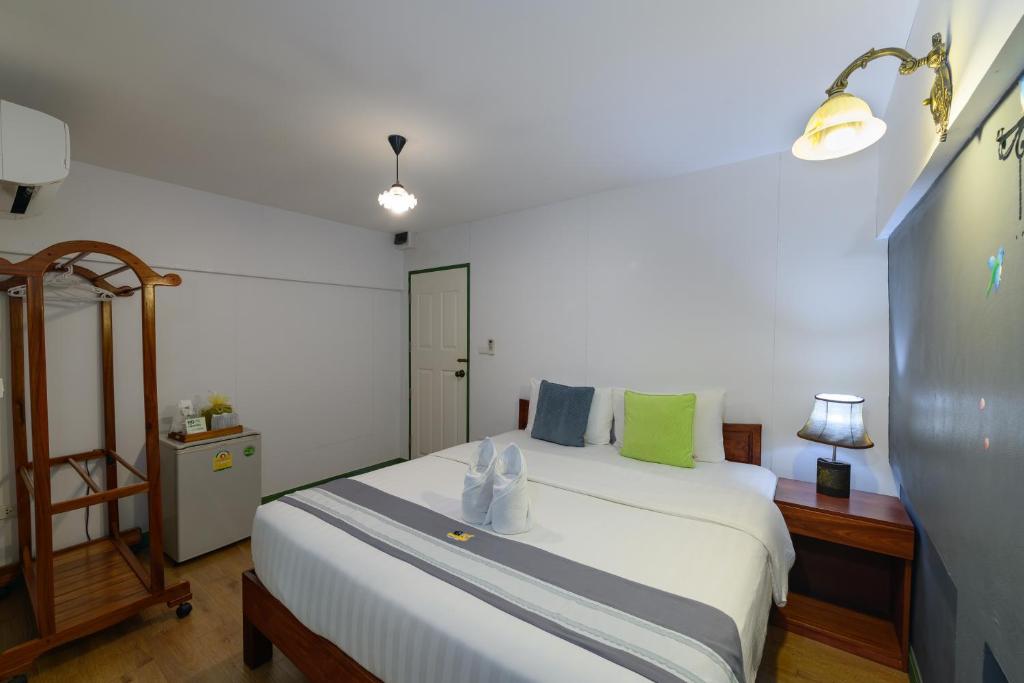 ein Schlafzimmer mit einem weißen Bett mit grünen und blauen Kissen in der Unterkunft 88 Backpackers Hua Hin in Hua Hin