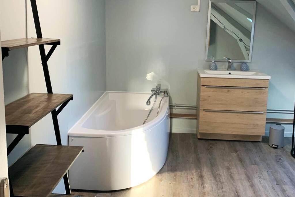 a large white tub in a bathroom with a sink at Caudry : Appartement spacieux plein centre in Caudry