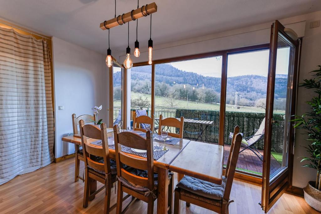 une salle à manger avec une table, des chaises et une grande fenêtre dans l'établissement Le Birdie - 3 bedroom apartment at the Golf de Giez and 5 minutes from the, à Giez