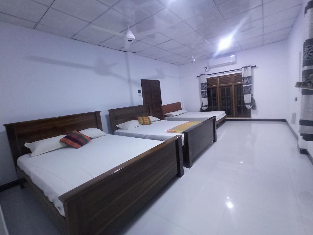 ein Zimmer mit 4 Betten und einer Tür darin in der Unterkunft Priyanna Guest, Forest view in Polonnaruwa