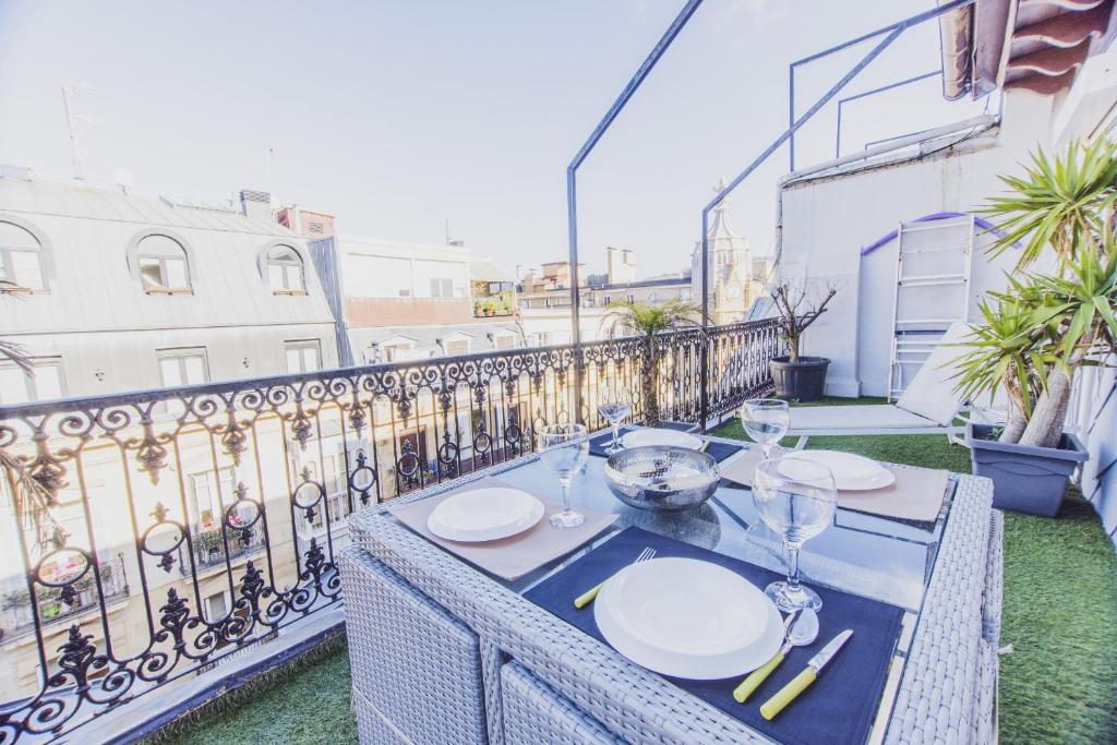 a table with plates and wine glasses on a balcony at Arrasate - Local Rentss in San Sebastián