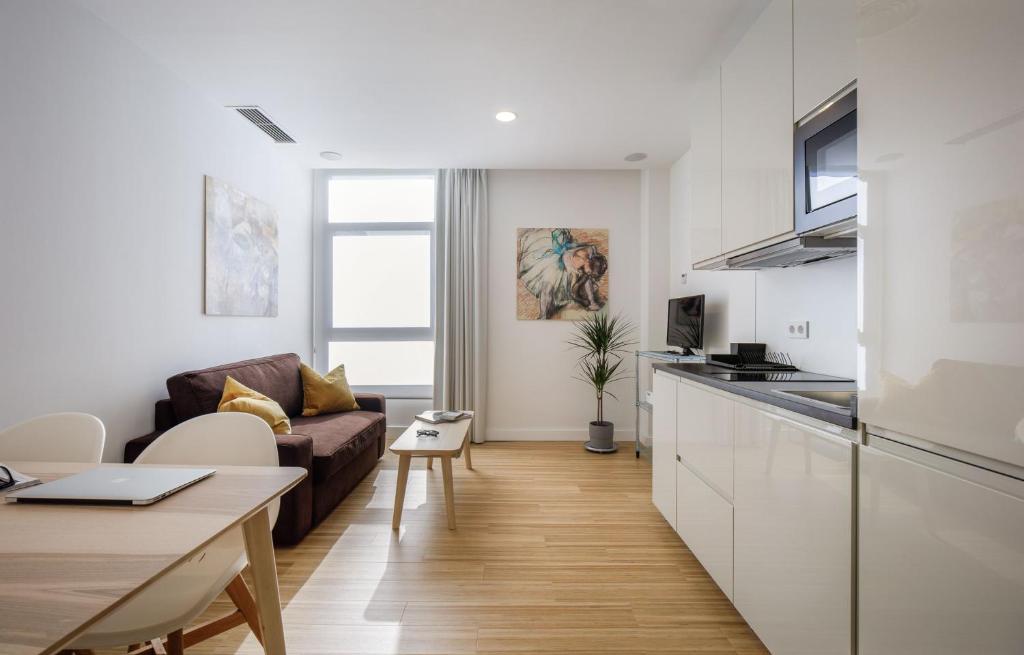 cocina y sala de estar con sofá y mesa en MUSH ROOM APARTAMENTOS en Sevilla