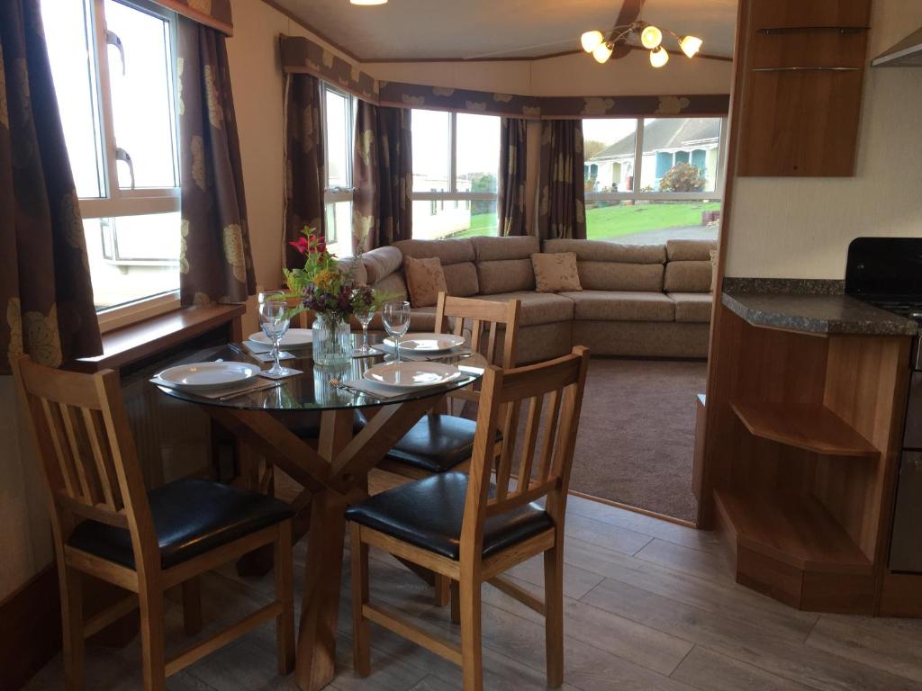 a dining room with a table and chairs and a couch at 'Hartland Caravan' with Sea Views in Bideford