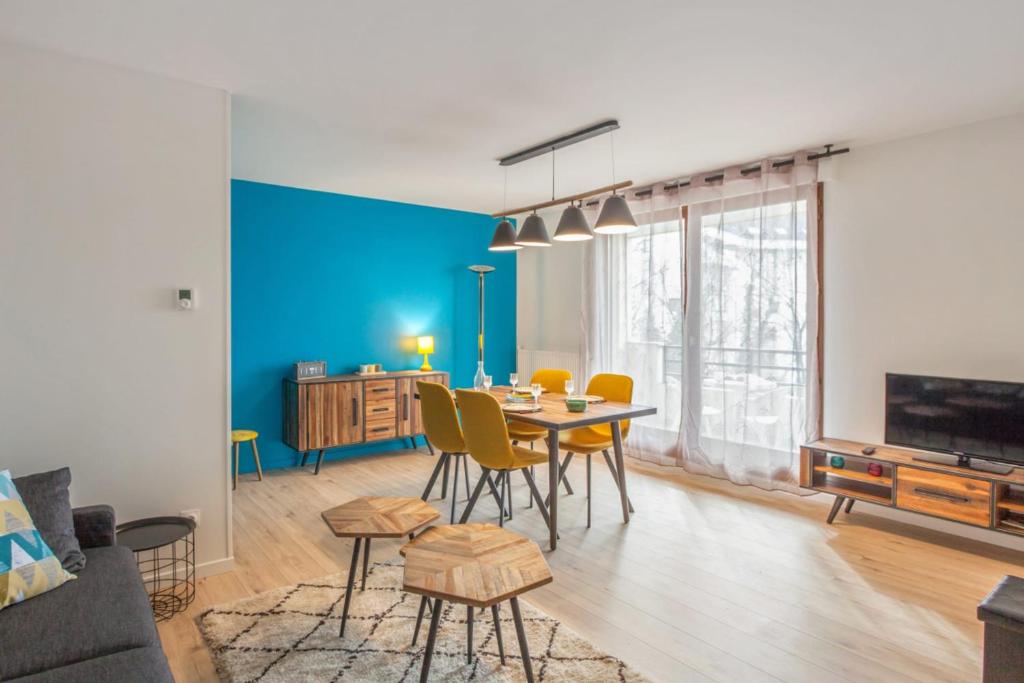 un salon avec une table et un mur bleu dans l'établissement Appartement Ribera - Welkeys, à Annecy