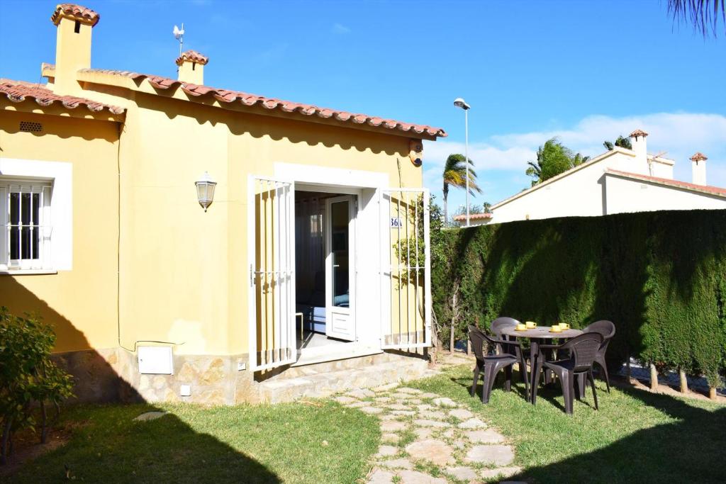 une terrasse avec une table et des chaises devant une maison dans l'établissement Anacasa Malibu Beach Oliva Nova MET AD1000, à Oliva