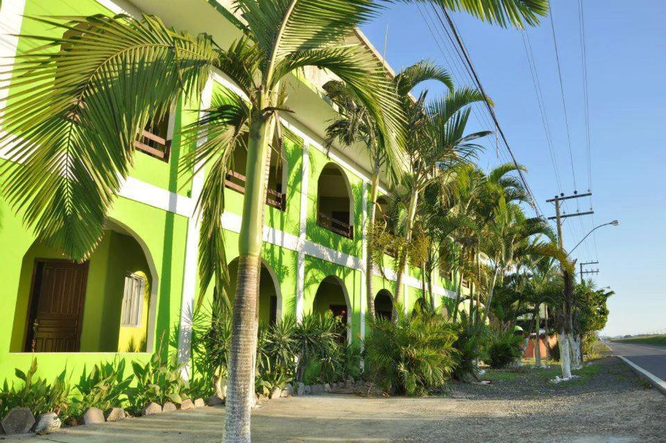 un bâtiment vert avec des palmiers devant lui dans l'établissement Hotel Paulista, à Barra Velha