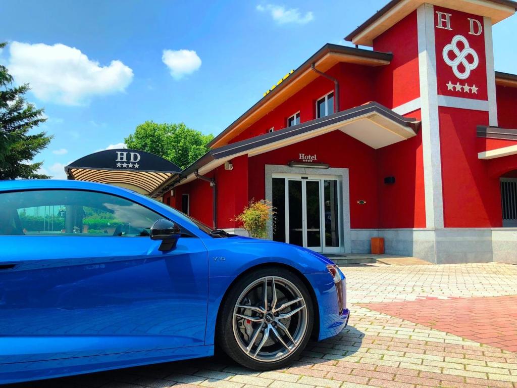 ein blaues Auto, das vor einem roten Gebäude parkt in der Unterkunft Hotel Daniel in Basiano