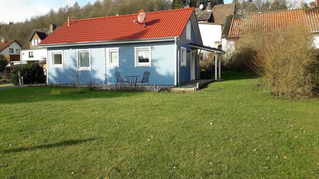 a blue house with a red roof in a yard at Ferienhaus Jütte in Ebergötzen
