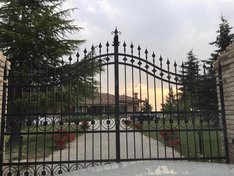 Una valla negra de hierro forjado con un jardín detrás. en Agriturismo Cà Mignone, en Urbino