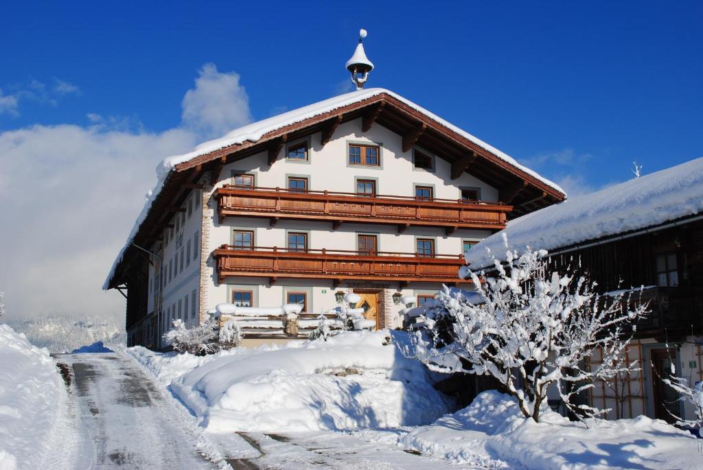 a large building covered in snow in front at Ferienheim Riedhof in Breitenbach am Inn
