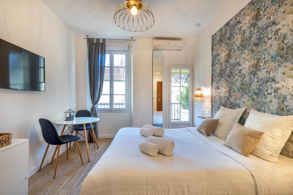 een slaapkamer met een groot wit bed en een tafel bij Agences des Résidences - Rue Commandant André in Cannes