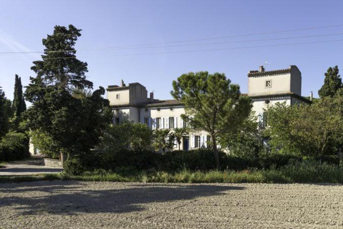 een groot wit huis met bomen ervoor bij Domaine de La Forçate in Villesiscle