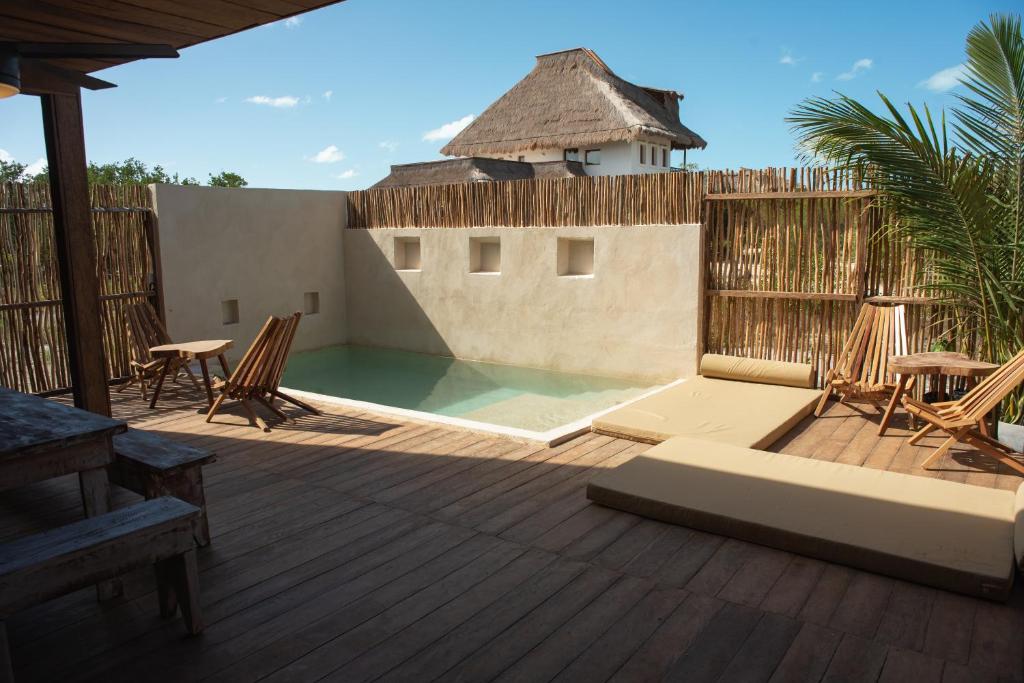 a patio with a pool and chairs on a deck at LaIsla Holbox Villa in Holbox Island