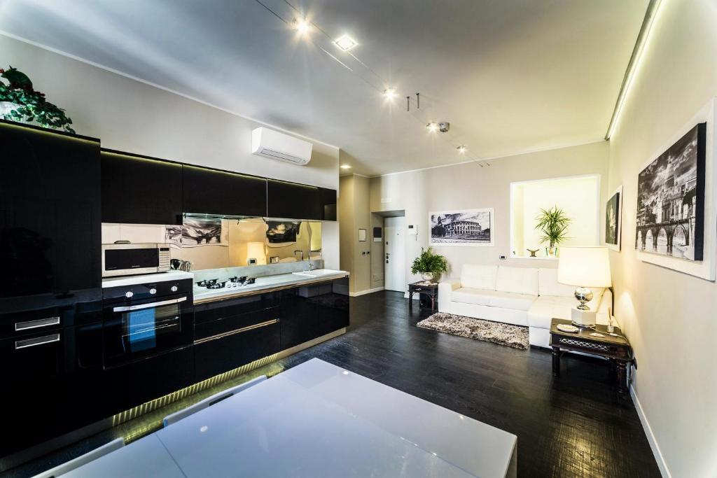 a large kitchen with black cabinets and a living room at Balestra Palace Apartment in Rome