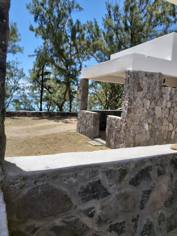 eine Steinmauer neben einem Gebäude mit Bäumen im Hintergrund in der Unterkunft Le Shanoa in Rodrigues Island