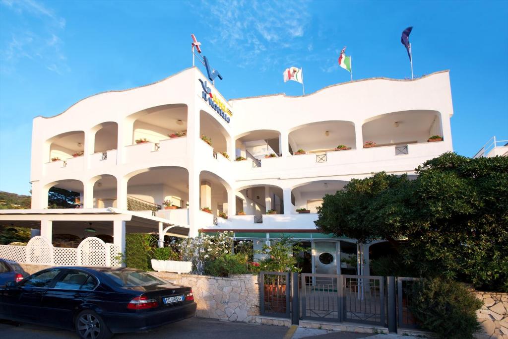 a white building with a car parked in front of it at Hotel Il Vascello in Marina Serra