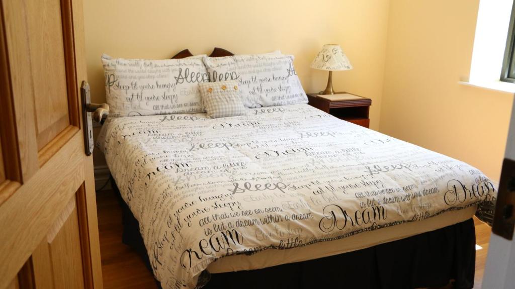 Una cama con un edredón blanco con escritura. en Emy Lake Apartment - near Castle Leslie, Glaslough en Monaghan