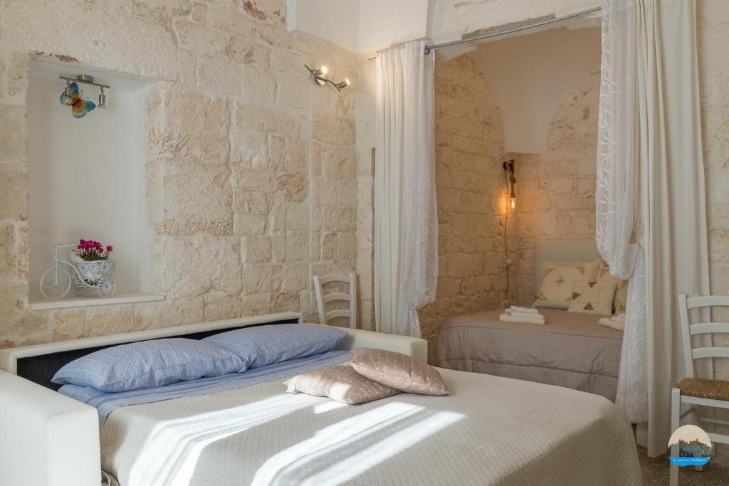 sypialnia z 2 łóżkami i kamienną ścianą w obiekcie Casa Filomena w mieście Ostuni