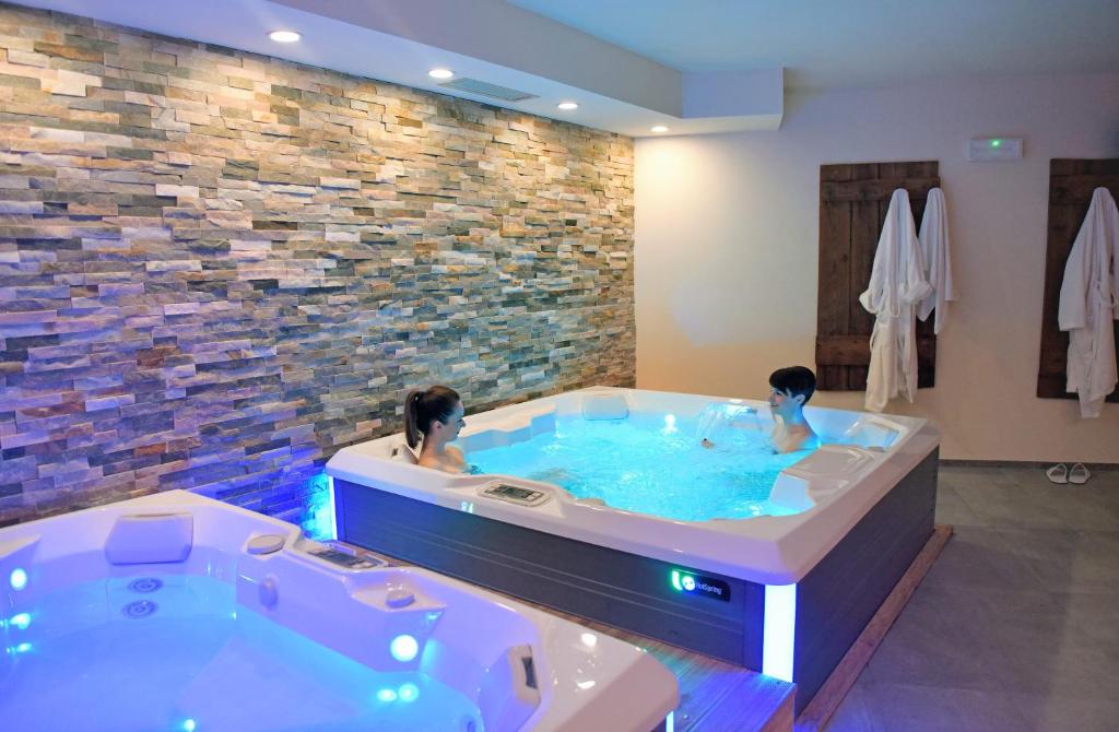 two people in a jacuzzi tub in a room at Alp Hotel Dolomiti in Dimaro
