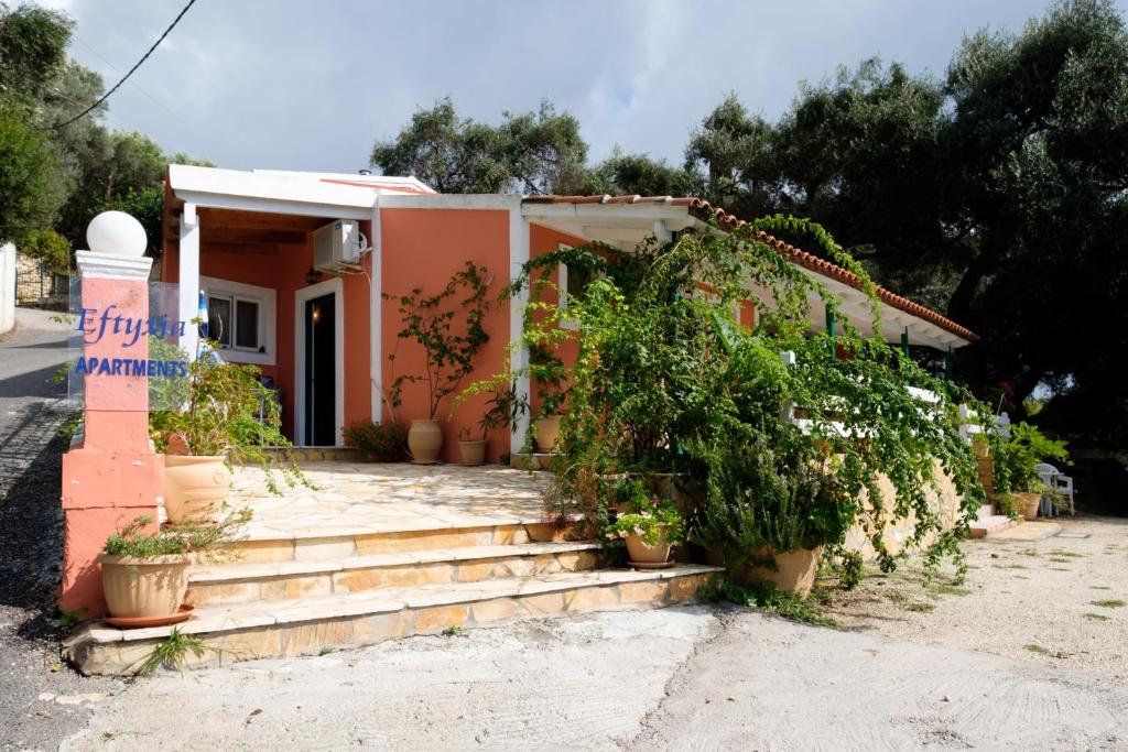 ein kleines Haus mit Topfpflanzen davor in der Unterkunft Eftyxia apartments in Paleokastritsa