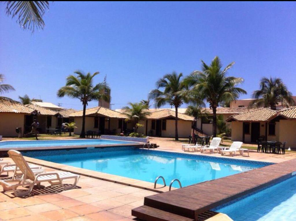 a large swimming pool with chairs and palm trees at Village Mamelucos frente para Praia do Flamengo in Salvador